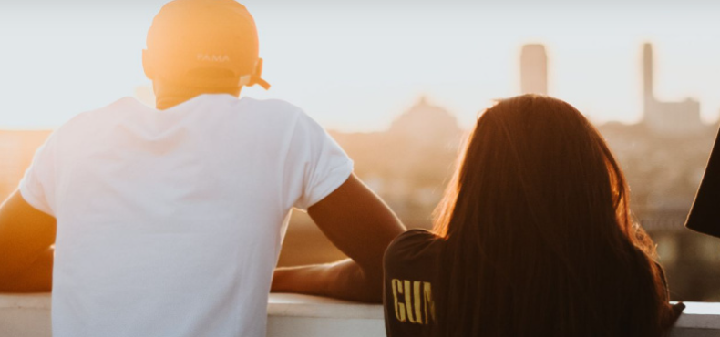 Jugendliche blicken an Mauer in Sonnenuntergang